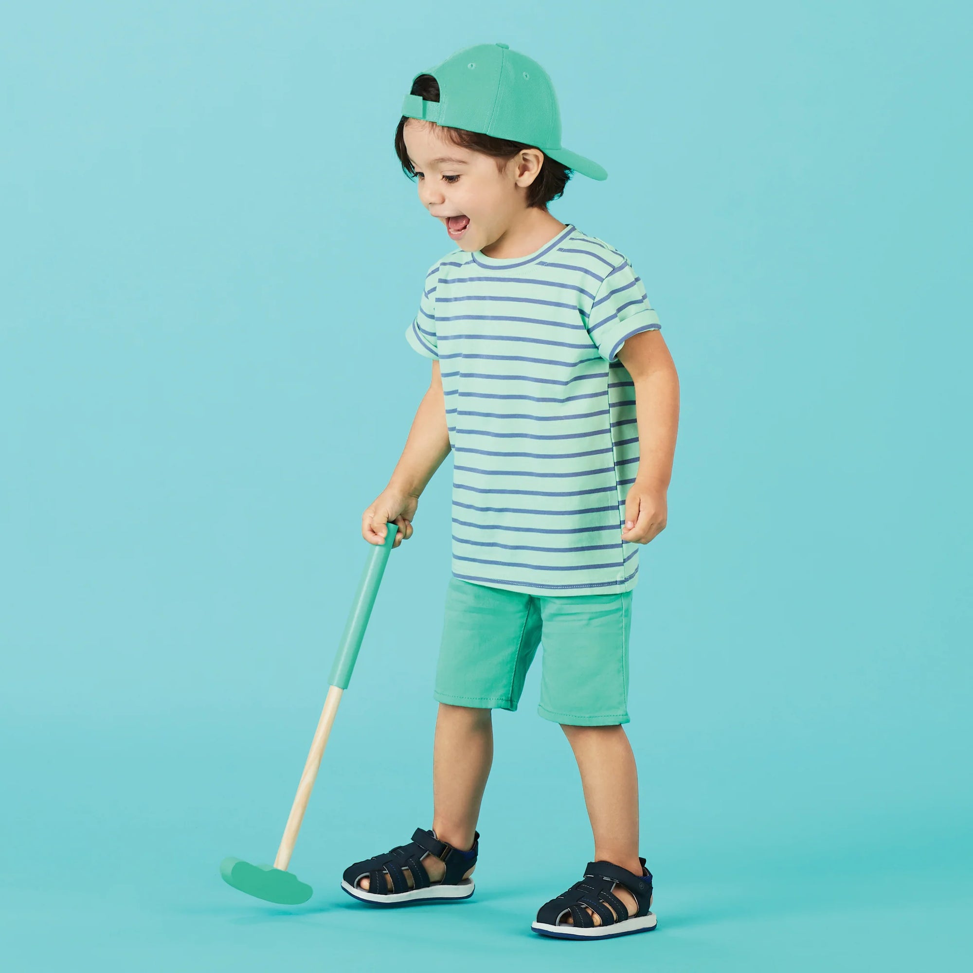 Little boy wearing the Stride Rite Paddy Sandal in navy, enjoying outdoor play with comfortable and durable shoes
